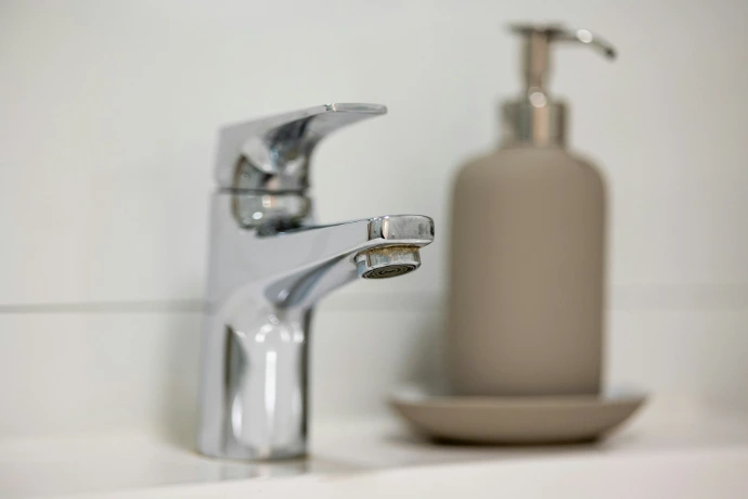 A bathroom sink with a soap dispenser next to it